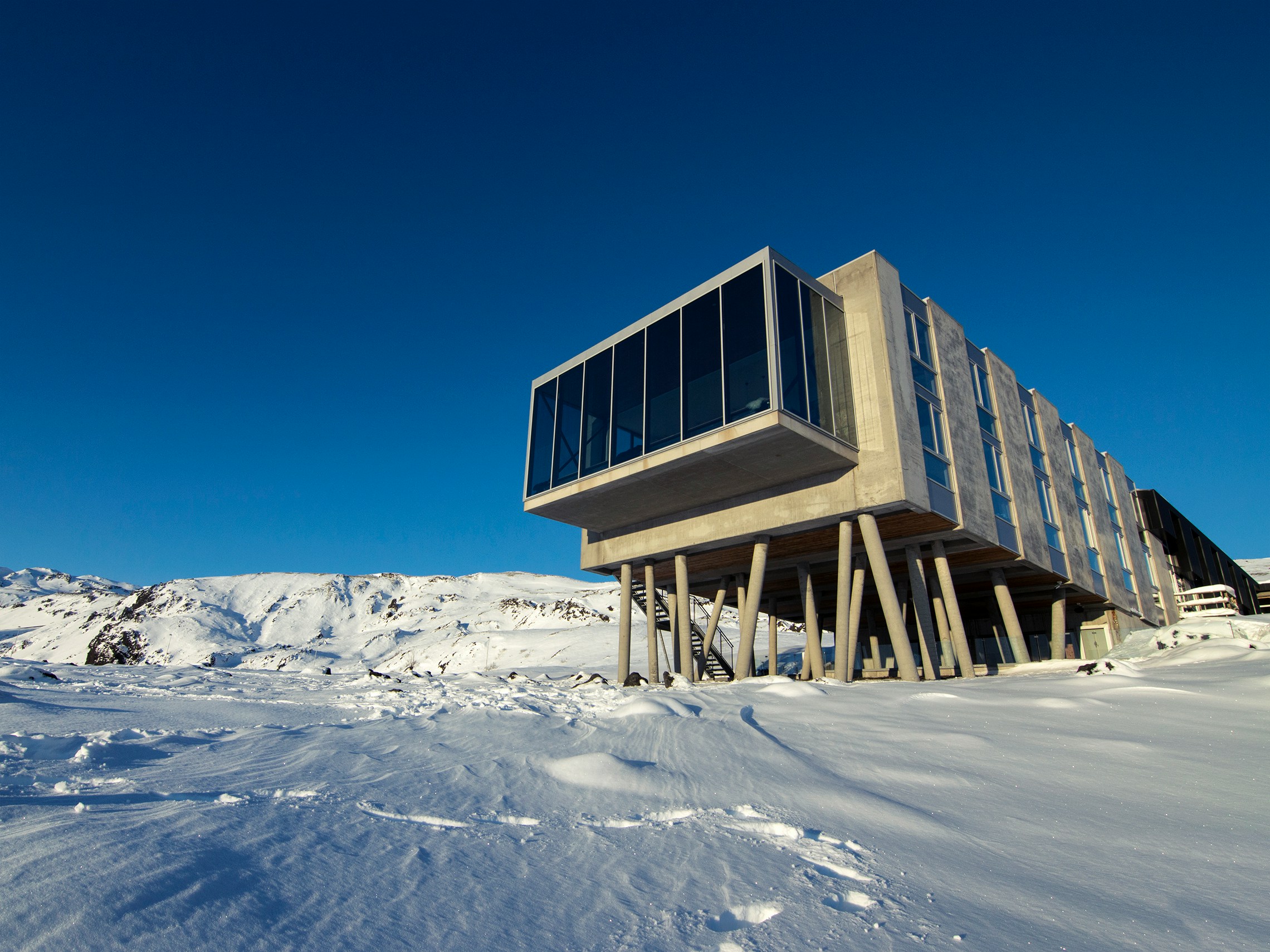 These luxury hotels in Iceland are the top accommodation options for travelers. 
Pictured: a grand resort in Iceland with floor to ceiling windows surrounded by snow and blue skies