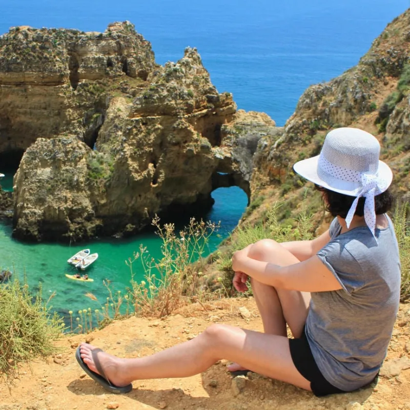 woman looks down on beautiful coast in algarve portugal