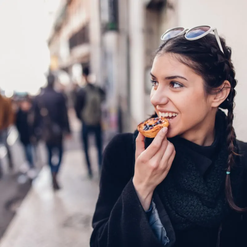 woman enjoys portuguese tart pastel de nata