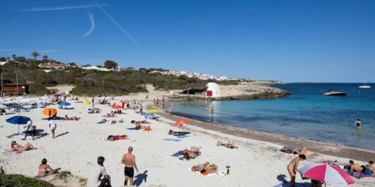 Tourists are flocking to Spain in record numbers, such as these seen sunbathing on the island of Menorca, giving the economy a huge boost (Jaime REINA)