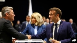 French President Emmanuel Macron, right, shakes hands with a polling station official during the European election, June 9, 2024 in Le Touquet-Paris-Plage, northern France.