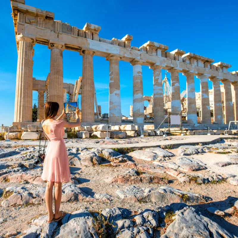 Young woman photographing with digital tablet Parthenon temple in Acropolis
