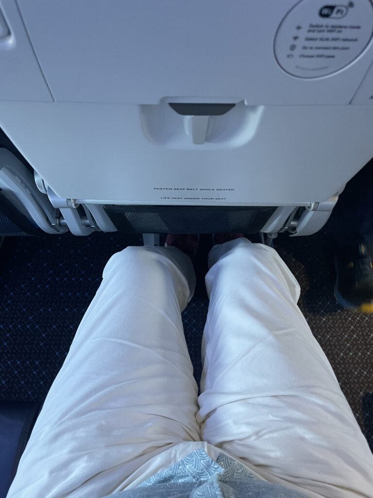 A man's knees are see in close proximity to the seat in front of him in Eurobiz