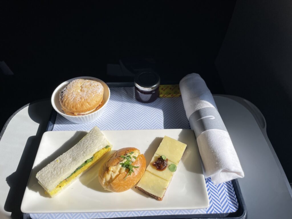 A British Airways tea service in-flight consists of cheese, a stuffed dinner roll and a long sandwich. 