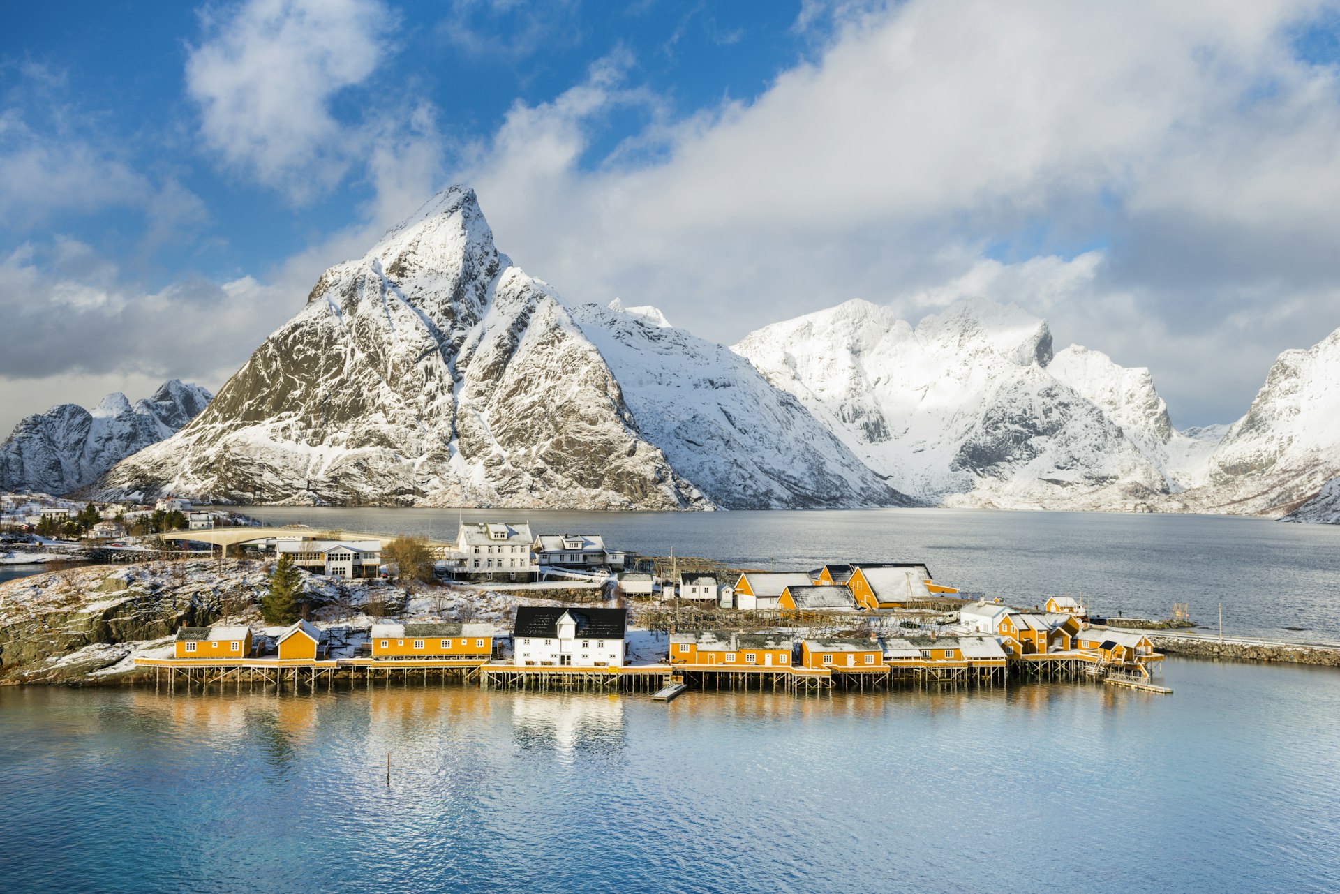 Rorbu huts on clear blue water with mountains behind in Sakrisoy.