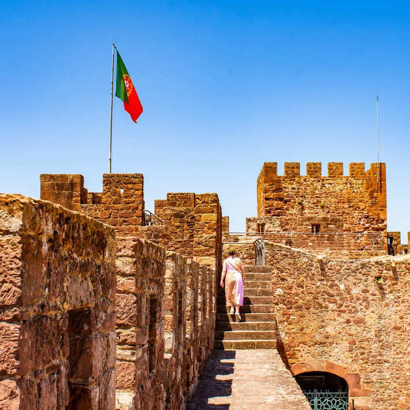 Young Woman Walking The Ramparts Of The Ancient Silves Castles In Silves, Algarve, Southern Portugal, Southern Europe