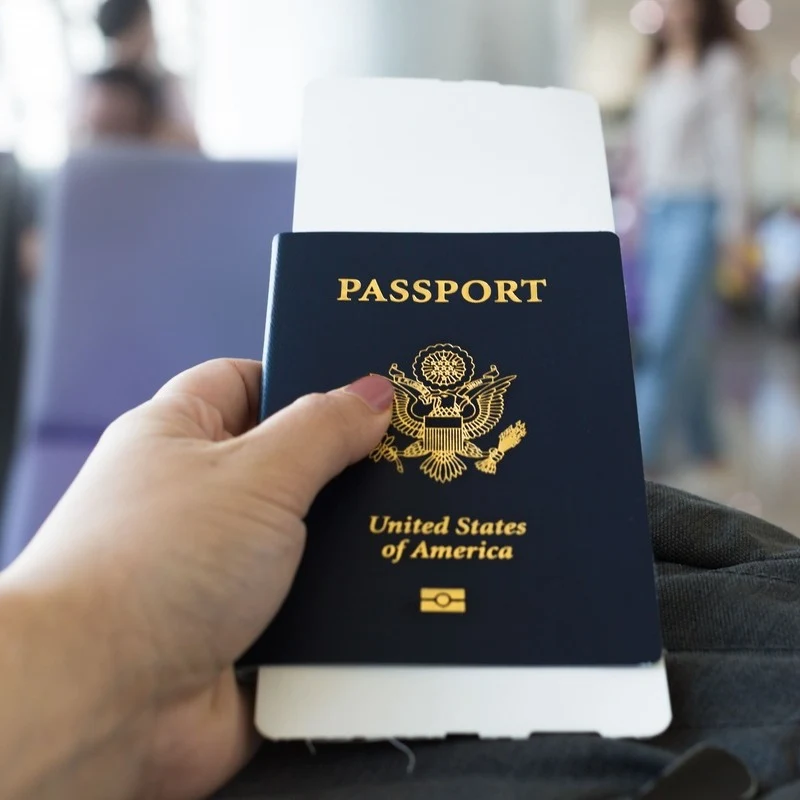 Young Female Traveler Holding Up A US Passport At The Airport