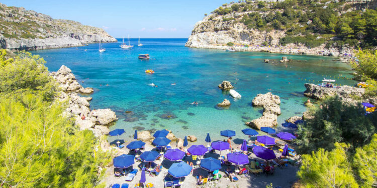 Gorgeous Beach In Rhodes Bounded By Turquoise Mediterranean Waters In The Dodecanese Group Of Islands In Greece, Southern Europe