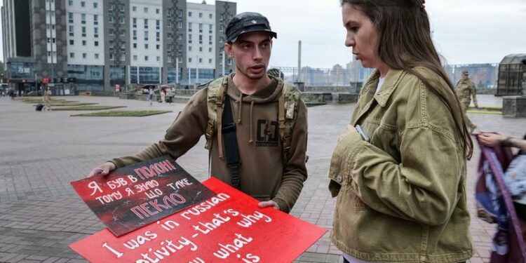 Svitlana Bilous and Illia Illiashenko look at posters before their bus tour to Switzerland to advocate for Ukrainian soldiers in Russian captivity in Kyiv