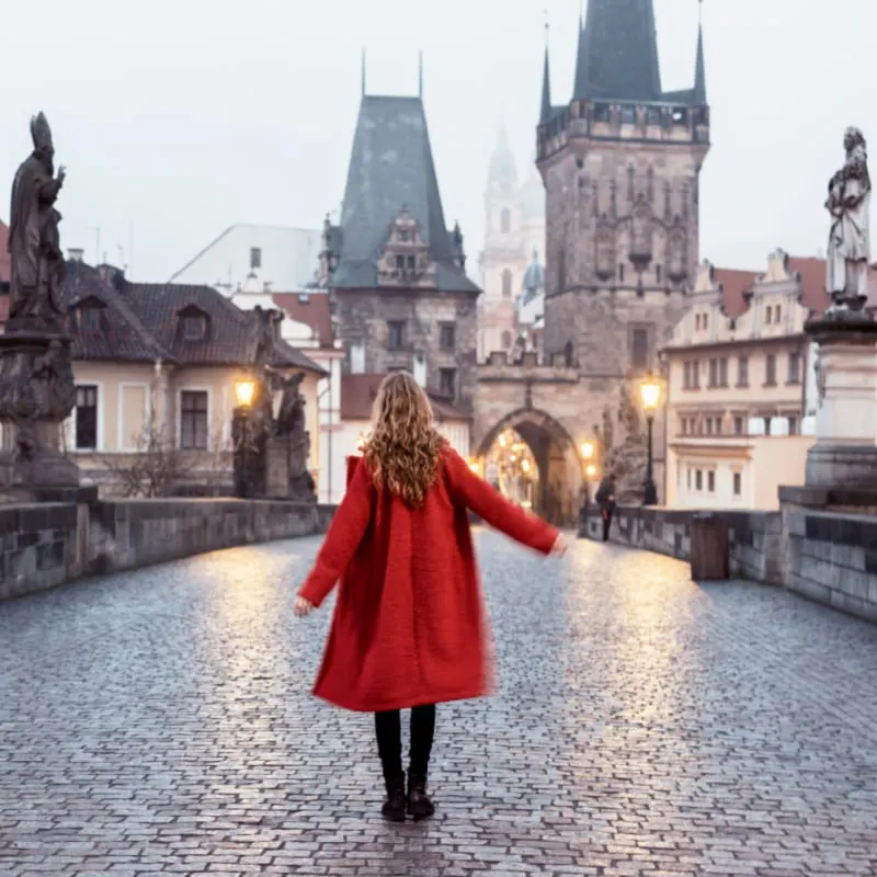 Female tourist walking on the Charles Bridge alone during a foggy morning in Prague, capital of Czech Republic