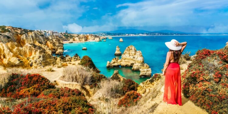 Woman in a red dress looking at the sea in the Algarve, Portugal