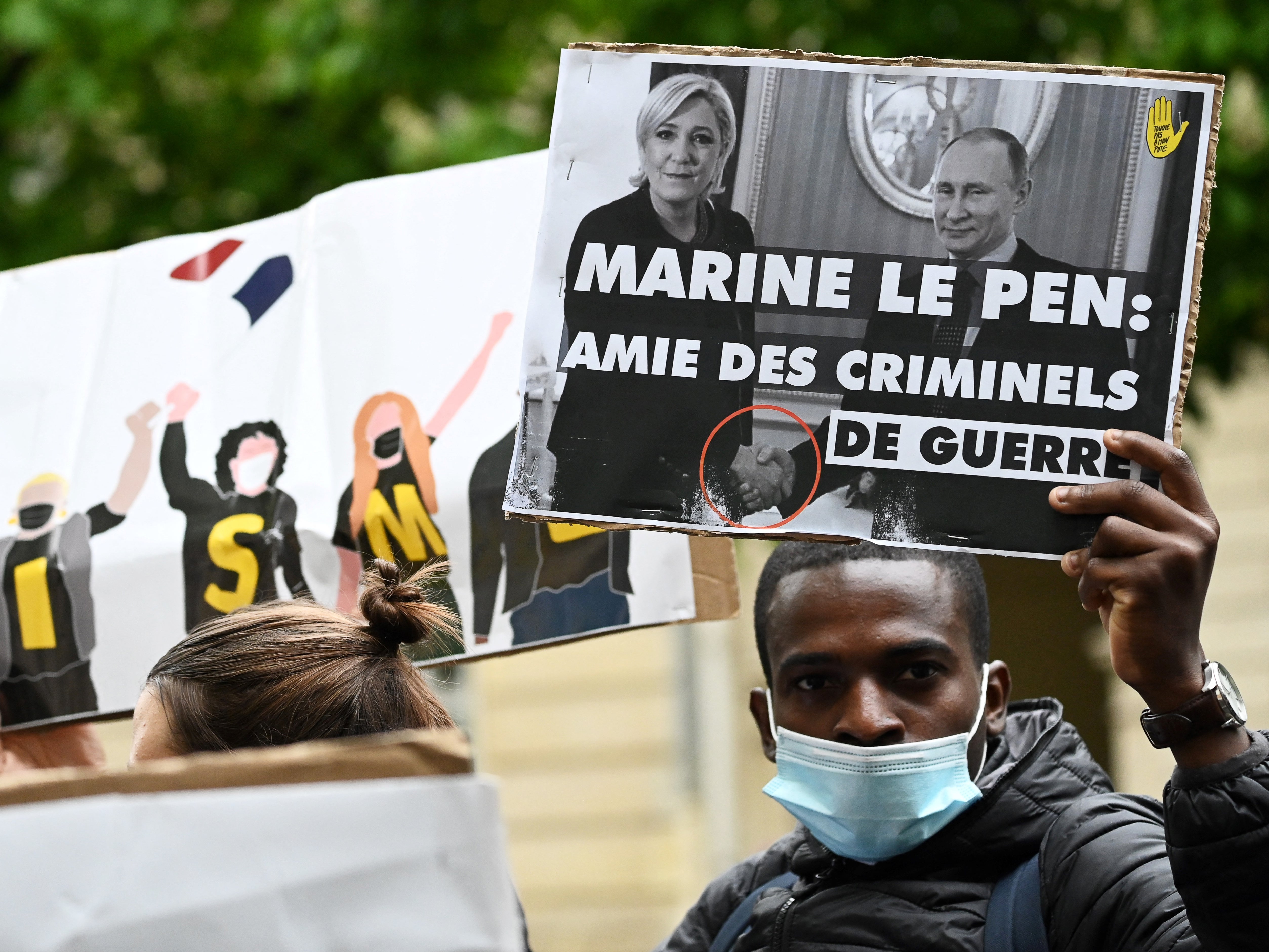 A protester holds a picture of Le Pen’s 2017 meeting with Vladimir Putin