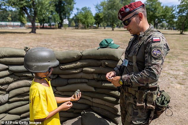 A Polish Scout holds a mockup grenade as he learns how to throw grenades during a military training day at the Polish Army's summer programme