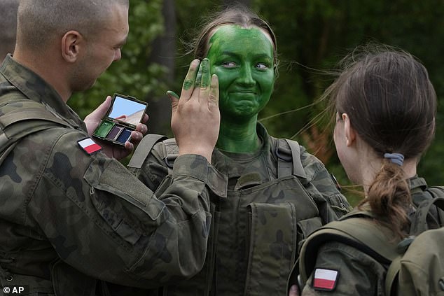 A Polish recruit has camouflage applied during training