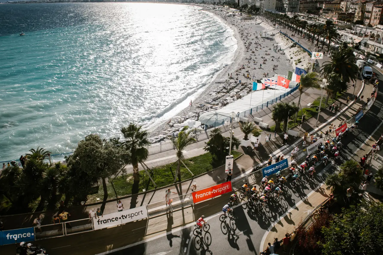 Tour de France in Nice, cyclist racing while beachgoers at the beach enjoying sea sun sand