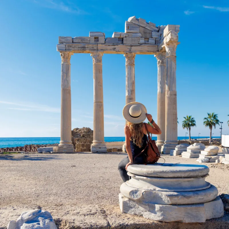 Woman overlooking ancient ruins and palm trees in Antalya, Turkey