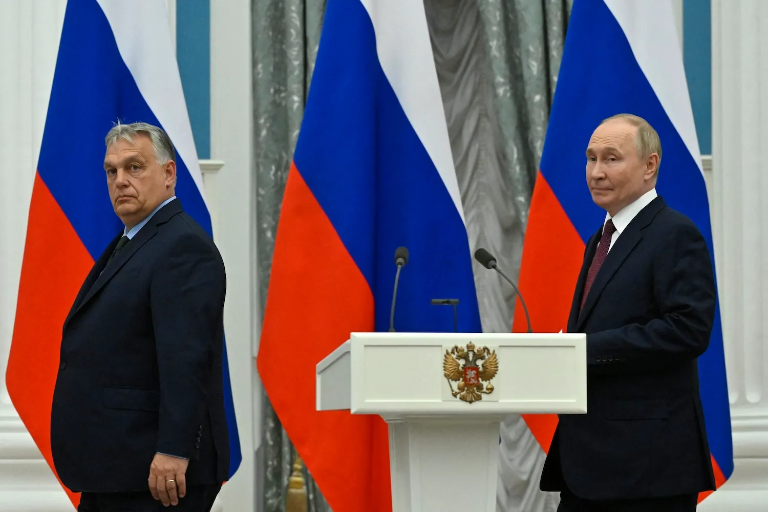 Orban and Putin walk near a podium.