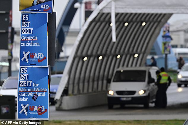 Election posters of the far right party AFD hang on a lamp post as German police officers control the traffic flow from Poland across the 