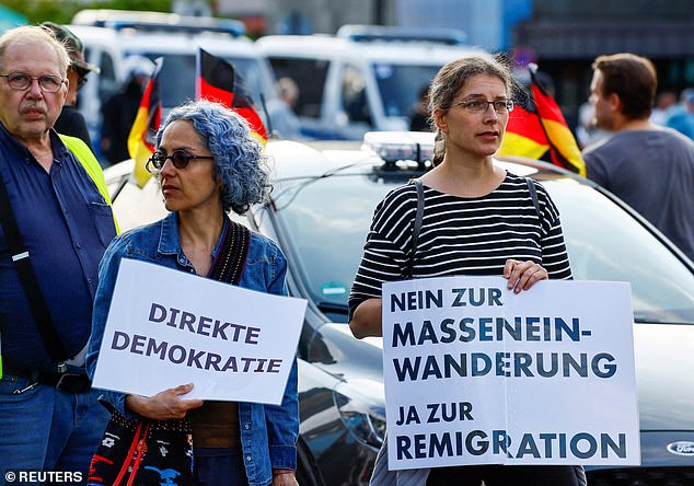 People hold banners that read 'Direct democracy' and 'No to mass immigration, yes to remigration' as far-Right protesters march through the streets of Solingen