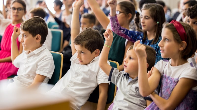 Primary children raise their hands at a devotional with Sister Tracy Y. Browning in Milan, Italy.