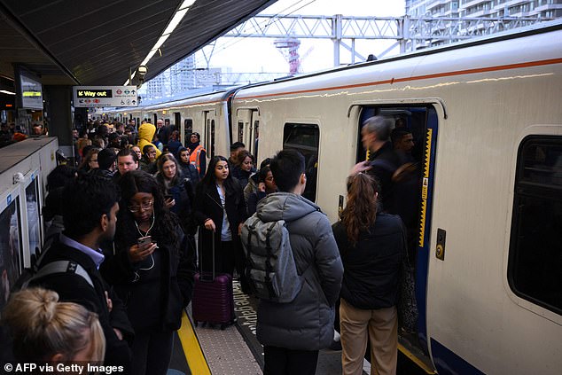 Commuters wait to board a train on a busy platform at Stratford station in November 2022