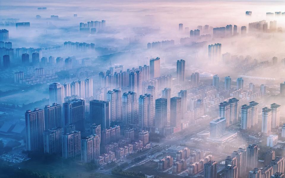 sunlight shining through the mist above residential buildings in the morning in Lianyungang in the country's Jiangsu province