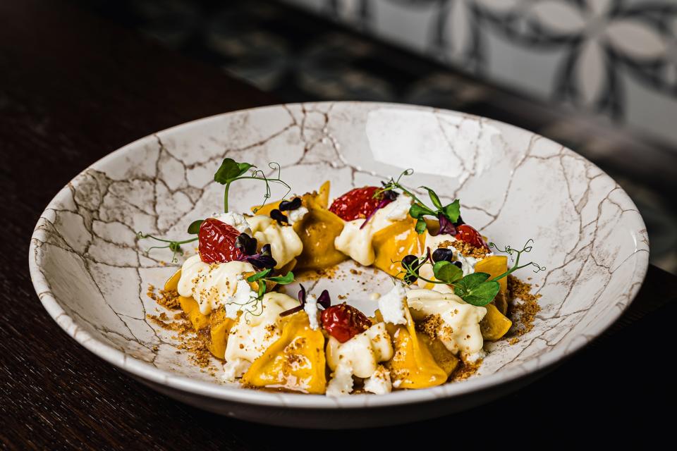 Pasta serves in a marble dish with tomatoes and cheese