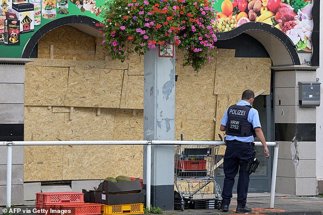 A police officer patrols in front of a food shop where a man rammed a van into it in Essen