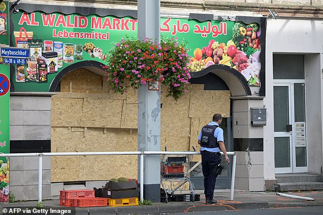 A police officer patrols in front of a food shop where a man rammed a van into it