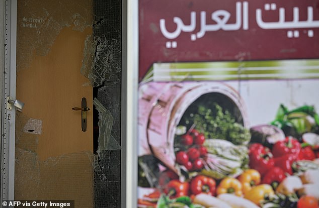 The broken glass of a door is seen at the food shop after the incident