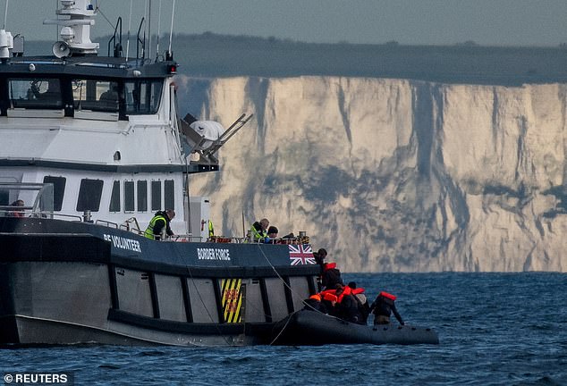 A British Border Force vessel picks up an inflatable dinghy carrying migrants in front of the white cliffs of Dover in the English Channel on May 4, 2024