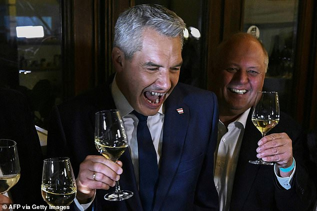 Austrian Chancellor Karl Nehammer shares a glass of wine with his party colleagues after exit poll figures were released for the country's general election on Sunday evening