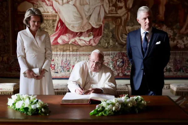 Pope Francis, sitting between Queen Mathilde and King Philippe of the Belgians, signs the Book of Honor at Laeken Castle on Sept. 27, 2024, during his trip to the country. Credit: Daniel Ibáñez/EWTN/Vatican Pool