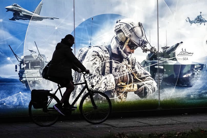 A man on a bicycle passes an advertisement at the headquarters of Germany's biggest arms manufacturer Rheinmetall AG in Duesseldorf, Germany