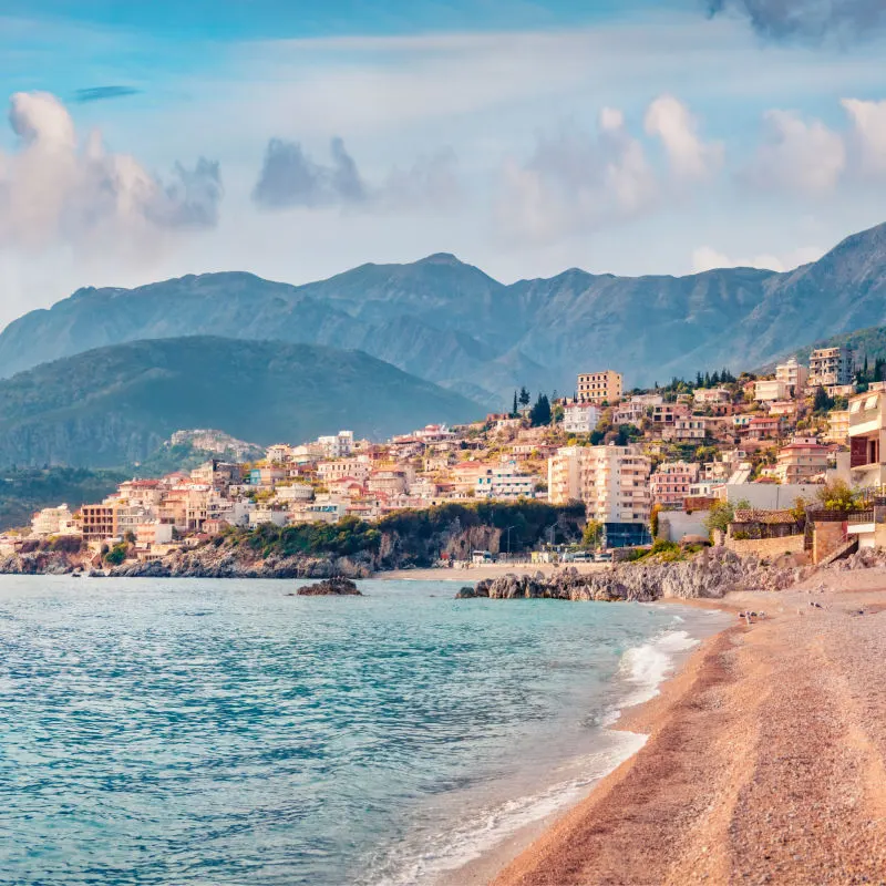 Beach with mountains and city in background in Albania.