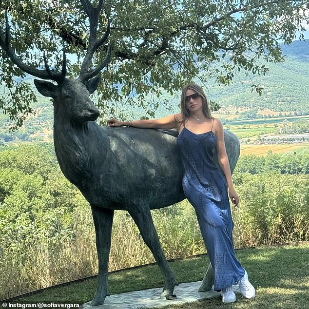 In this image she was seen in a blue dress next to a sculpture of a deer