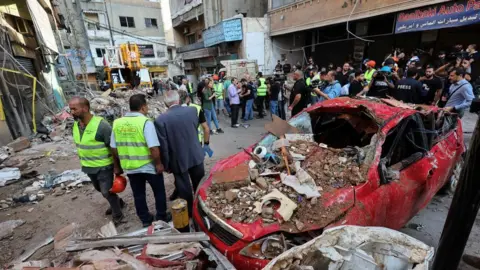 Reuters People stand next to a destroyed car, at the site of an Israeli strike in Beirut's southern suburbs, Lebanon September 24, 2024.