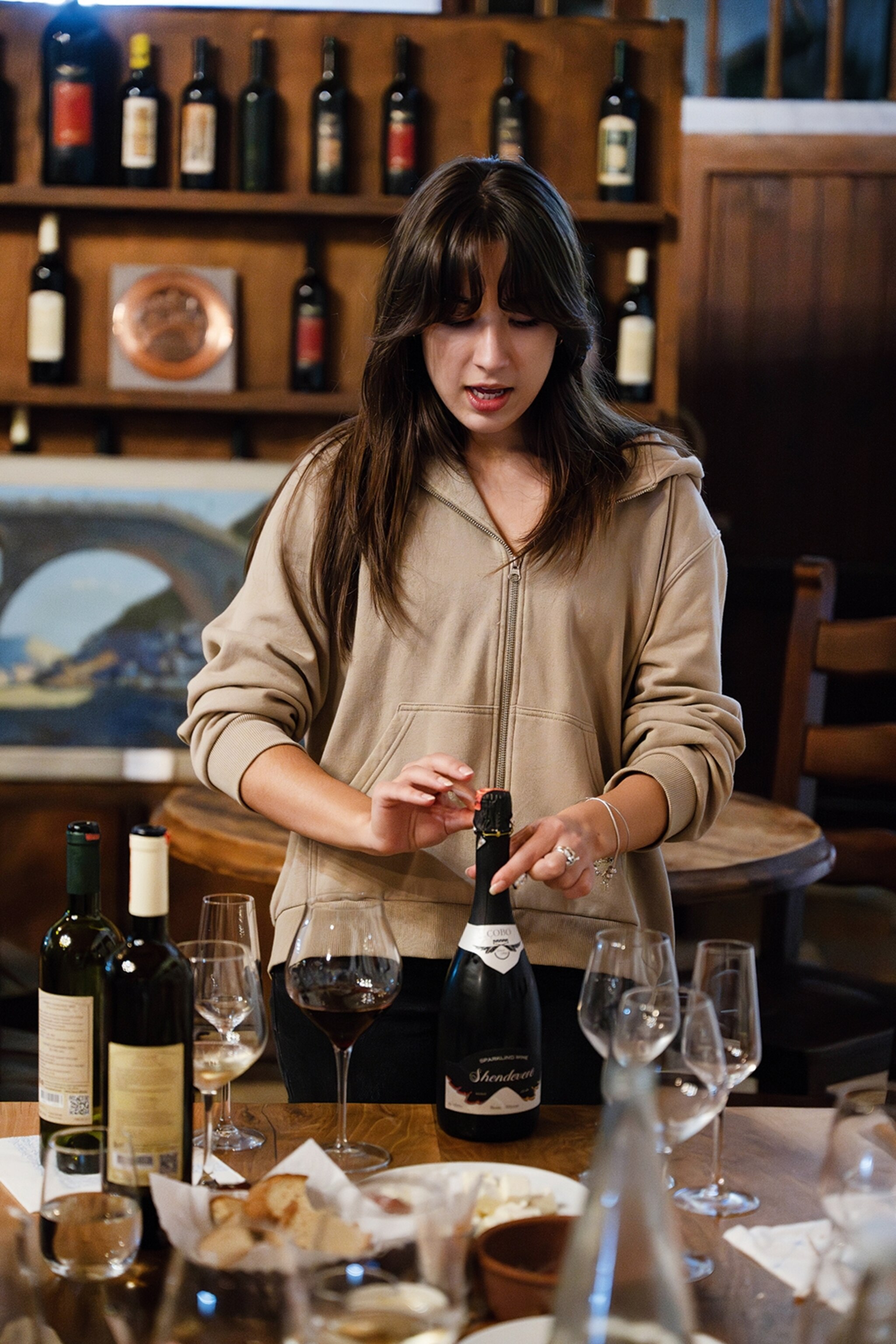 A female wine expert opening a bottle of wine in a tasting class.