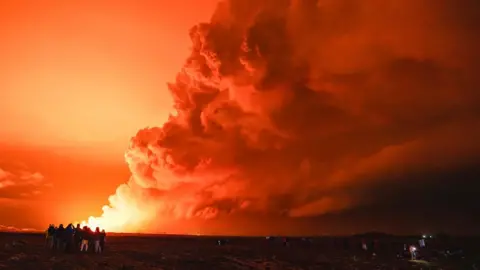 Getty Images People gather to watch as molten lava flows out from a fissure on the Reykjanes peninsula, 16 March