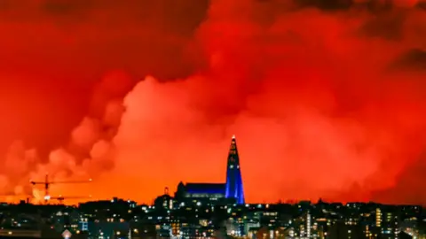 Getty Images The skyline of Reykjavik turns orange from the lava flowing from a fissure caused by a volcanic eruption