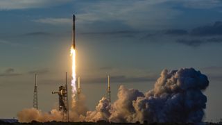 a white and black rocket launches into a darkening sky