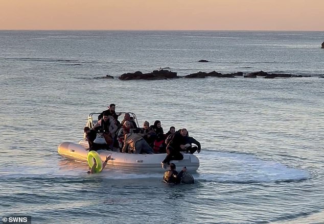 The boat contained around a dozen men and women without safety gear and two appeared to have babies strapped to their fronts while one person can be seen using a pool inflatable for support