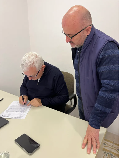 Simon Mercieca standing over as John Dalli signs Mercieca's nomination. Photo: Simon Mercieca blog