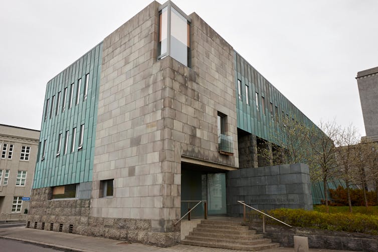 A building of pale green and grey stone seen at an angle.