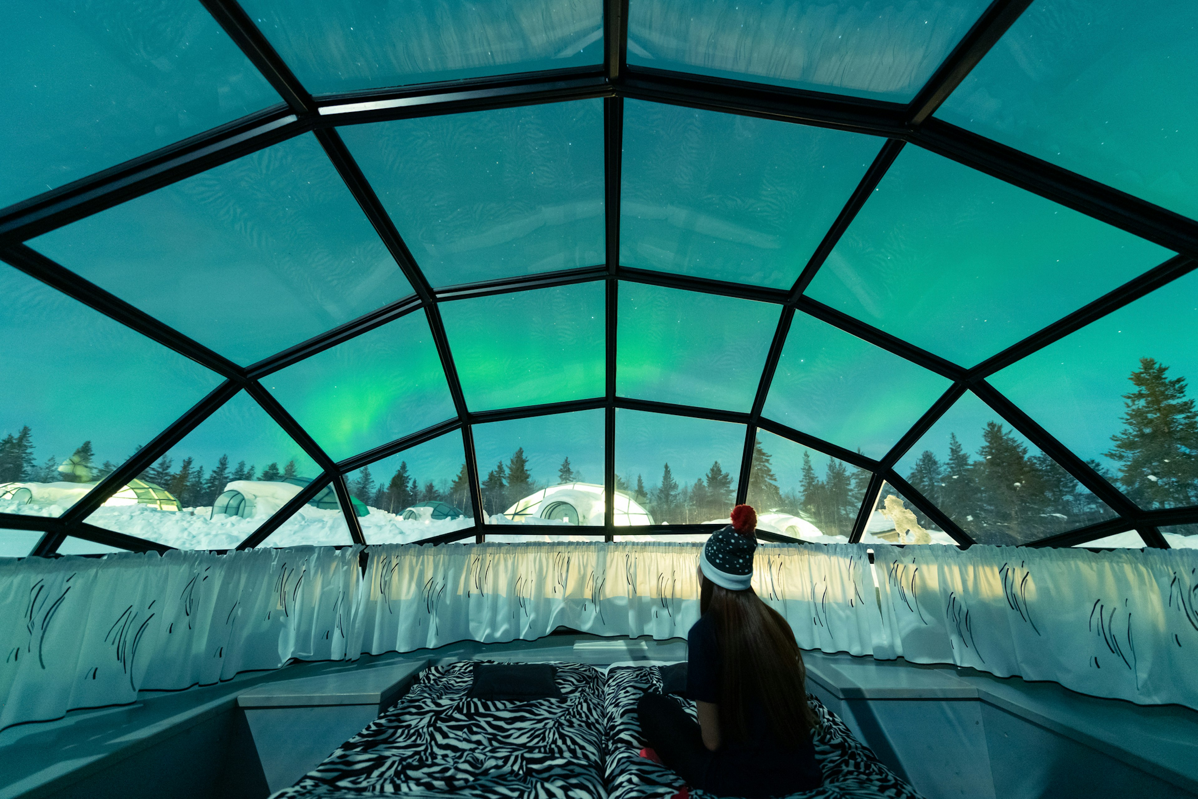 A woman watches the northern lights from inside a glass igloo in a resort in Finnish Lapland.