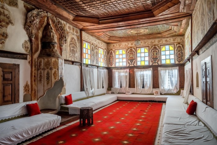 A room with red carpet and ornate carved ceiling and frescoed walls