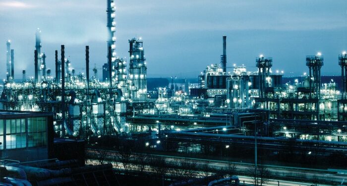 A petrochemical plant at night. The lights are greenish blue.