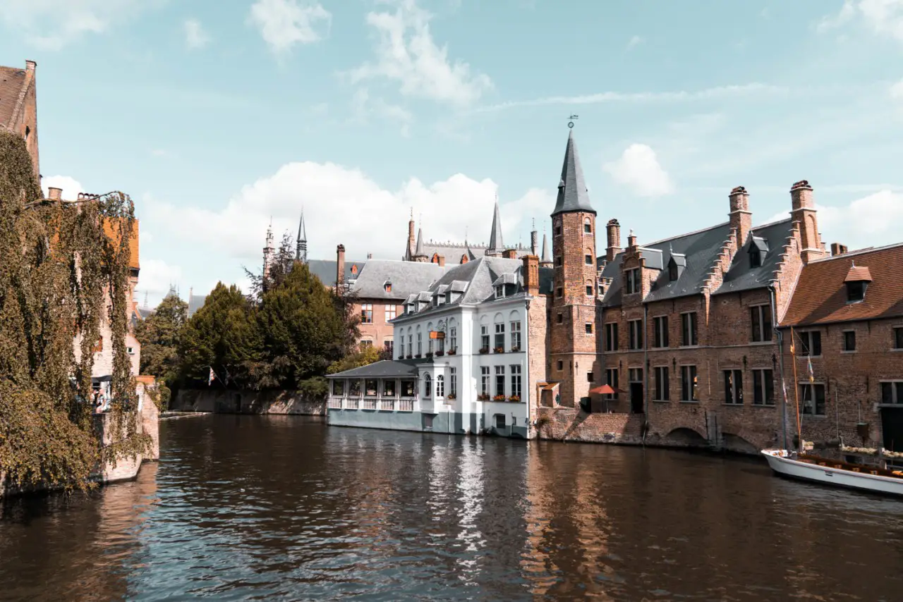 Scenic view of Bruges, Belgium, with historic buildings along a tranquil canal on a sunny day.