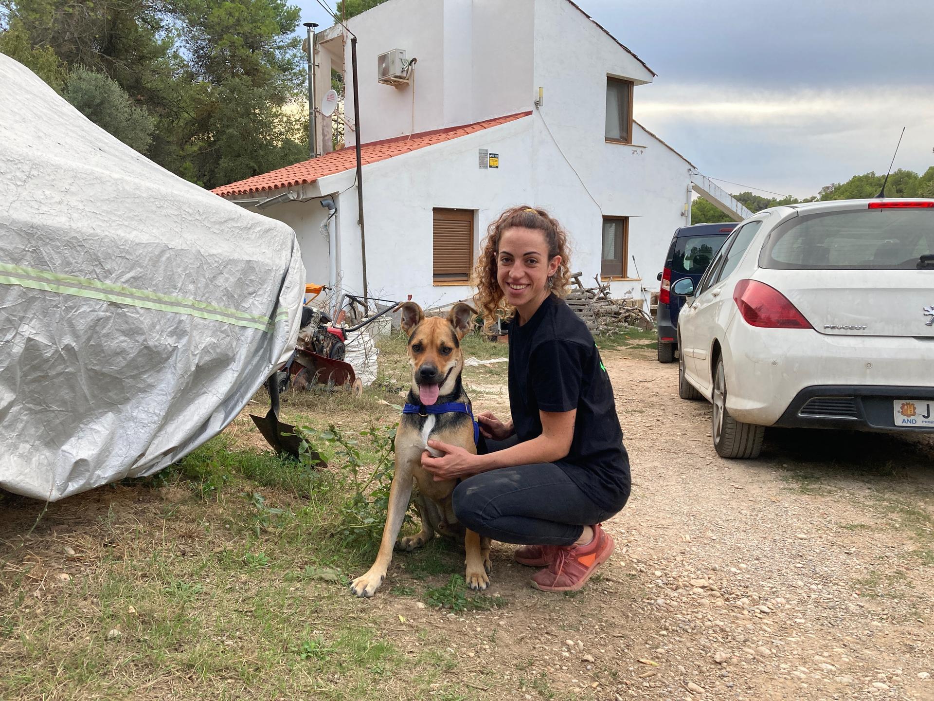 A woman kneeling and posing with her dog