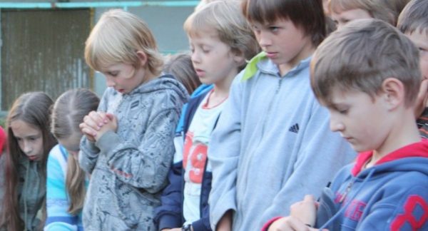 Lithuania : Children bow their heads for a prayer after a late-night devotional at Camp Ruta. | (photo by Erik Tryggestad)